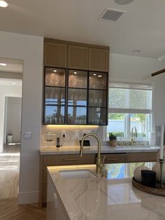 a kitchen with marble counter tops and wooden cabinetry next to a large open window