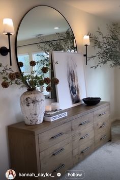 a large mirror sitting on top of a dresser next to a vase filled with flowers