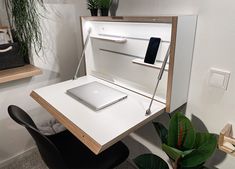 an open laptop computer sitting on top of a white desk next to a potted plant