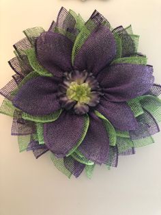 a purple flower with green leaves is hanging on the wall