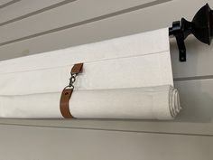 a white curtain hanging on the side of a house with a brown leather strap around it