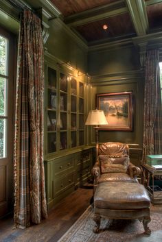 a living room with green walls and wood flooring, leather furniture and large windows