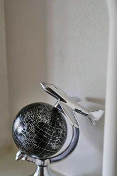 a small black and white globe sitting on top of a metal stand in front of a wall