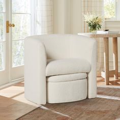 a white chair sitting on top of a wooden floor next to a table and window