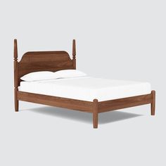 a wooden bed frame with white sheets and pillows on top of it, against a gray background