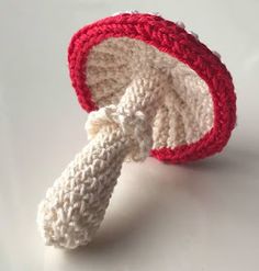 a crocheted red and white hat with a knot on the top, sitting on a table