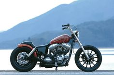 a red and black motorcycle parked on the side of a road with mountains in the background