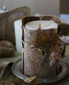 a candle that is sitting on a plate next to some leaves and other things in the background