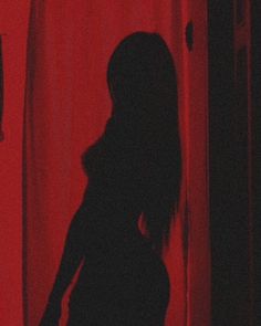 the silhouette of a woman standing in front of a red curtain with her arms outstretched