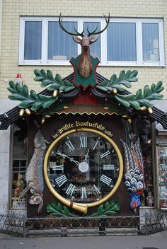 a large clock on the side of a building with deer head and antlers above it