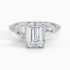 an emerald cut diamond ring with three diamonds around it