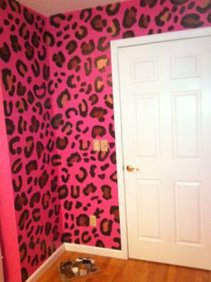 a room with pink and brown leopard print wallpaper on the walls, door to another room