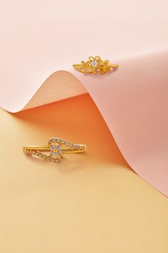 two gold rings sitting on top of a pink paper with an image of a flower