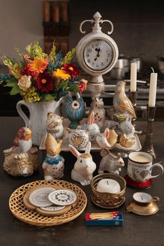 a table topped with lots of different types of figurines next to a clock