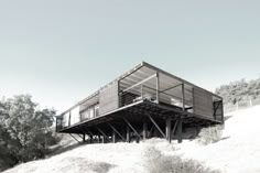 a large wooden structure sitting on top of a sandy hill next to trees and bushes