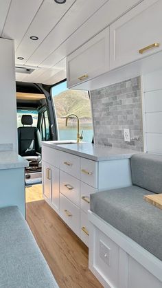 the interior of a camper van with white cabinets and wood flooring is shown