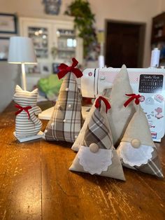 three small christmas trees sitting on top of a wooden table next to a sewing machine