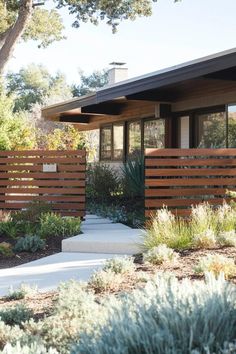 a modern home with wood slats in the front yard and landscaping on the side