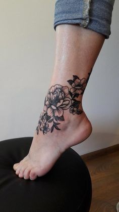 a woman's foot with a flower tattoo on her left ankle and the bottom part of her leg