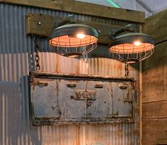 two industrial style lights hanging from the ceiling over a toilet in a bathroom with corrugated walls