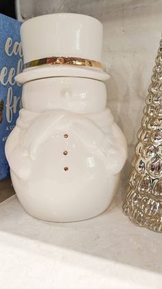 a snowman cookie jar sitting on top of a counter next to a christmas tree