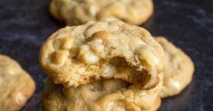 several cookies with white chocolate chips are on a black surface