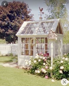 a small white house sitting in the middle of a yard with flowers growing around it