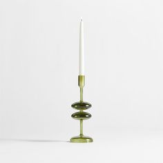 a candle holder with two candles in it on a white background, one is green and the other is gold