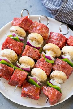 meat and vegetable kabobs on a plate with toothpicks in the middle