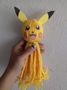 someone is holding up a yellow knitted pikachu