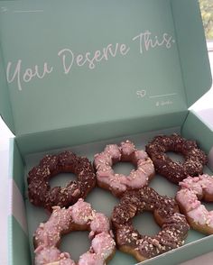 there are six donuts in the box with pink frosting and sprinkles