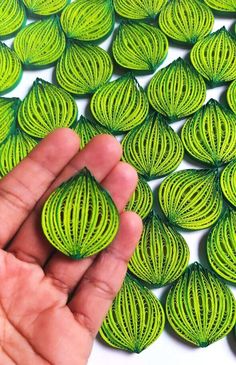 a hand is holding a green piece of string art