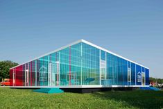 a colorful glass building sitting on top of a lush green field