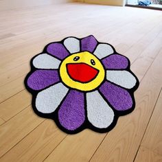 a purple and yellow flower shaped rug on the floor in front of a wooden floor