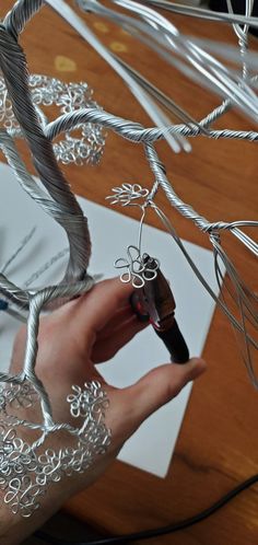 a person holding a pen and wire sculpture