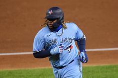 a baseball player running on the field with his bat in hand and wearing a blue uniform