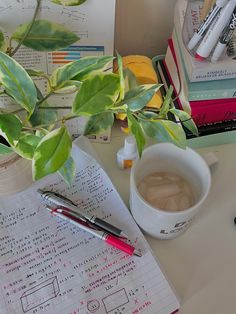 a cup of coffee sitting on top of a desk next to a pen and paper