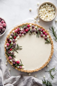 a tart with cranberries and marshmallows on it next to bowls of candies