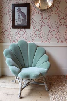 a blue shell chair sitting in front of a wall with red and white designs on it