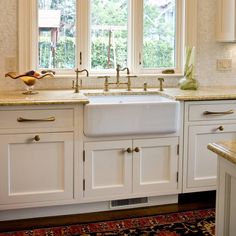 a kitchen with white cabinets and marble counter tops is pictured in this image, the sink has gold faucets on it