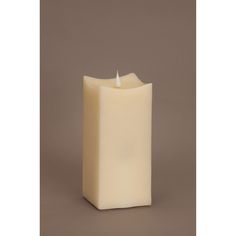 a white pillar candle on a brown background