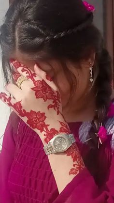 a woman with henna on her hand covering her face