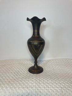 a black vase sitting on top of a bed