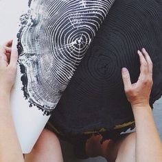 two hands are holding up a large black and white pillow that looks like a fingerprint