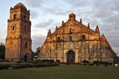 an old church in the middle of a grassy area with two towers on each side