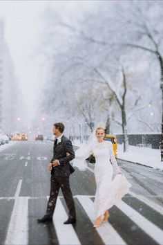 a bride and groom crossing the street in the snow