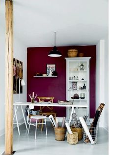 a dining room with red walls and white furniture in the center, along with wicker baskets on the floor