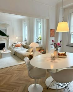 a living room filled with furniture and a fire place next to a dining table on top of a hard wood floor