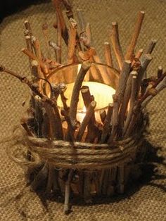 a candle that is sitting in a basket on the ground with sticks sticking out of it