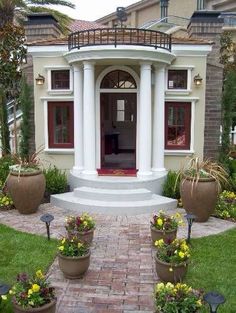 a house with many potted plants in front of it and an entry way leading to the door